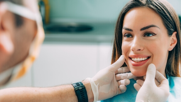 Cosmetic dentist in Frisco looking at a smiling patient