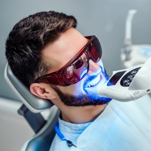 Man getting professional teeth whitening in dental chair