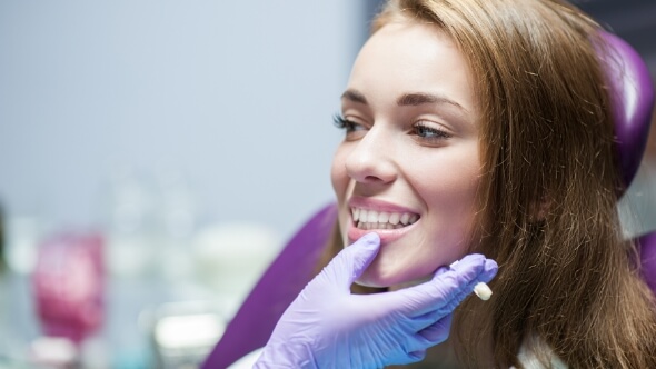 Dentist looking at a patient smiling with dental crowns in Frisco