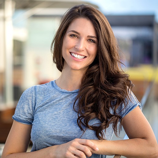 Woman in blue shirt leaning on a fence and smiling