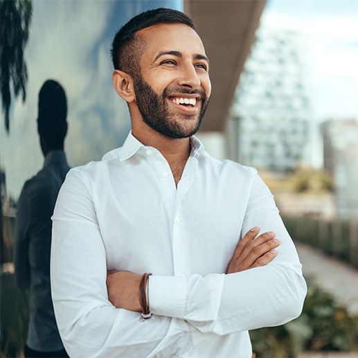 Man in white shirt smiling with arms folded