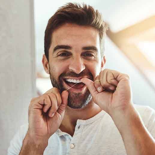 Man smiling while flossing his teeth