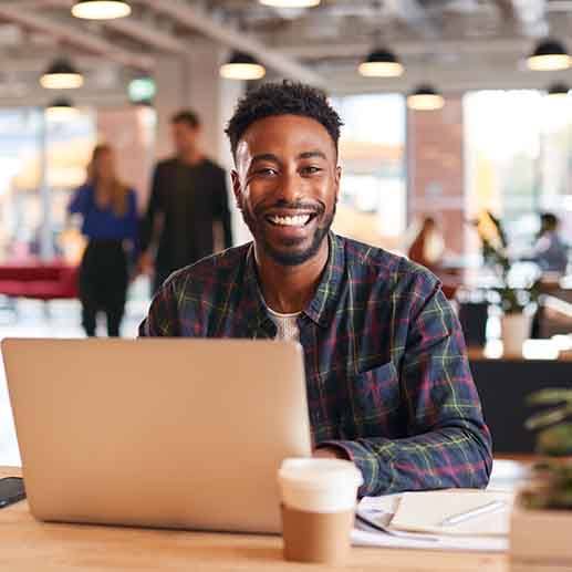 Man smiling while working on laptop in office