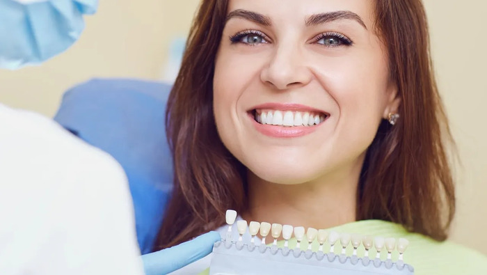 Woman smiling next to dentist holding shade guide