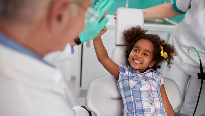 Young girl giving a high five to her dentist